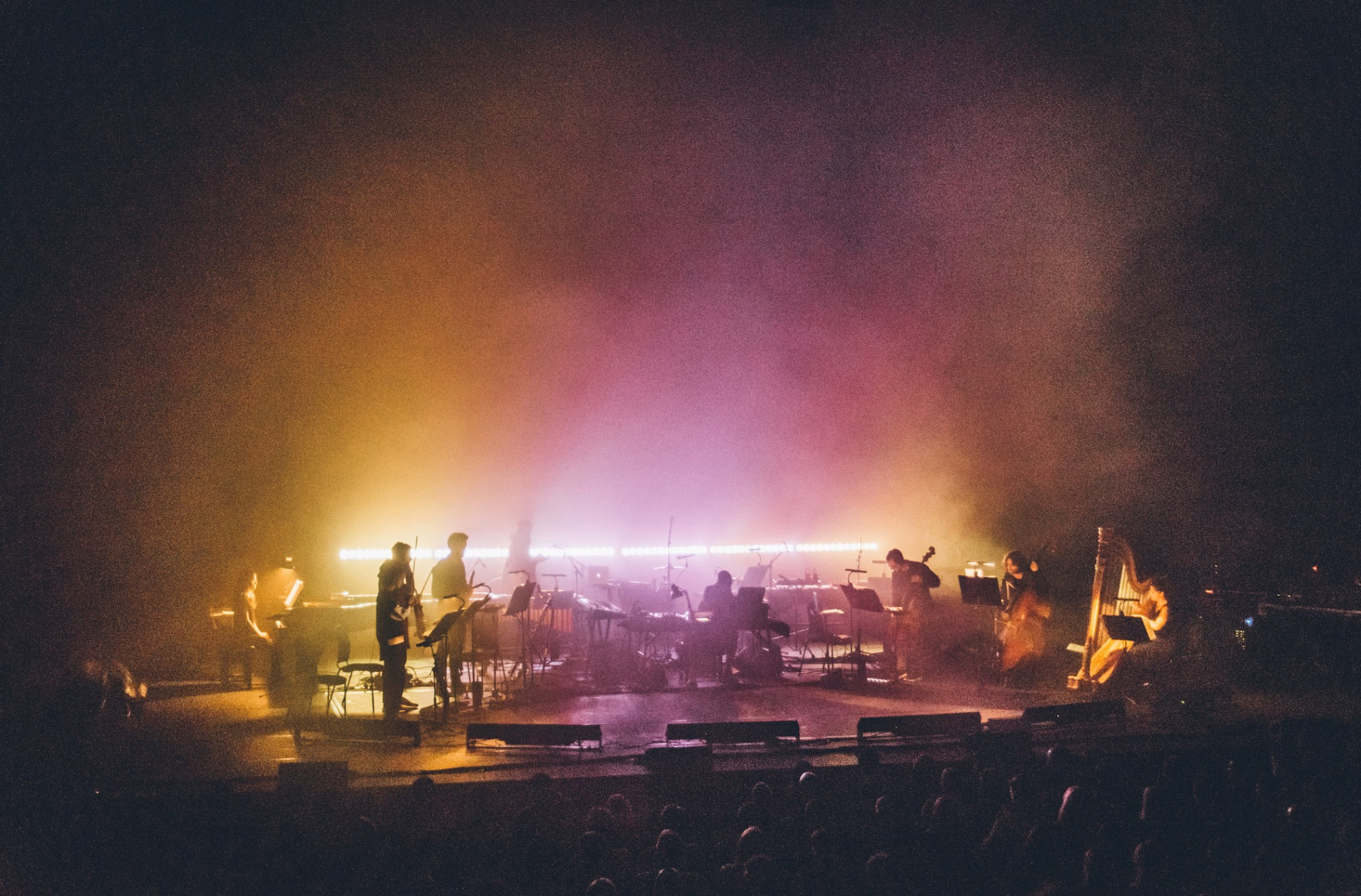 Orchestra on stage bathed in amber and pink haze